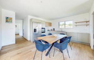 a kitchen and dining room with a wooden table and blue chairs at Gorgeous Home In Vielle Saint Girons in Saint-Girons-en-Marensin