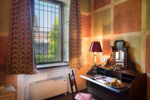 een kamer met een bureau, een raam en een tafel bij Palazzo Castiglioni Luxury Suites in Mantova