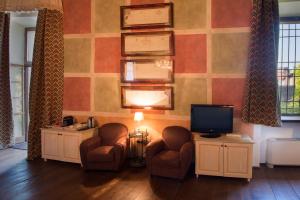 a living room with two chairs and a television at Palazzo Castiglioni Luxury Suites in Mantova