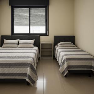 two beds in a room with a window at Apto aconchegante, central, prox ao carrefour in Santa Maria