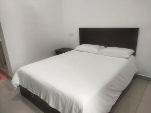 a bedroom with a white bed with a black headboard at S&P Hotel in Tampin