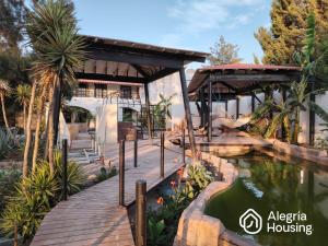 a house with a wooden walkway next to a pond at 102 Arje Suites Campestre by Alegría Housing in Las Pilas +19 photos
