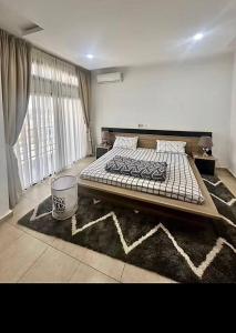 ein Schlafzimmer mit einem großen Bett und einem Teppich in der Unterkunft OBDP House in Abidjan