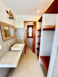 ein Badezimmer mit einem Waschbecken, einem Spiegel und Regalen in der Unterkunft Vila Carnaúba - Piscina e luxo in Fortim