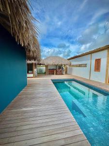 einen Pool mit einem Holzsteg neben einem Gebäude in der Unterkunft Vila Carnaúba - Piscina e luxo in Fortim