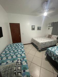 une chambre avec deux lits et un ventilateur de plafond dans l'établissement JL Suites Temporada, à Arraial do Cabo 39 autres photos