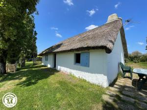 a building with a thatched roof and a bench at Charmante chaumière traditionnelle dans le Marais breton - FR-1-426-584 in Beauvoir-sur-Mer