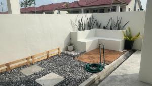 a garden with a hose on the ground next to a fence at Dedaun Homestay Perlis in Kangar