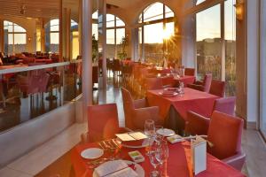 un restaurante con mesas y sillas rojas y ventanas en Miyako Resort Shima Bayside Terrace, en Shima