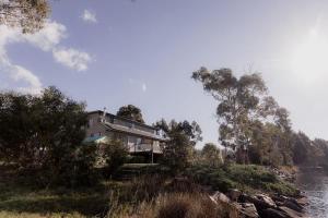 una casa en una colina al lado de un cuerpo de agua en Little Swanport River Haven, en Little Swanport
