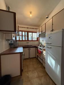 a kitchen with a white refrigerator and a sink at Chalet Pino azul in Villa Carlos Paz