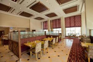 a restaurant with tables and chairs in a room at Copthorne Al Jahra Hotel & Resort in Kuwait