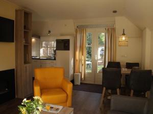 a living room with an orange chair and a kitchen at Forest Villa in Herperduin with Bubble Bath in Herpen