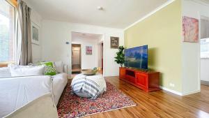 Una sala de estar con un sofá y un televisor de pantalla plana. en Lucerne Escape by GoodLive, en Frankston