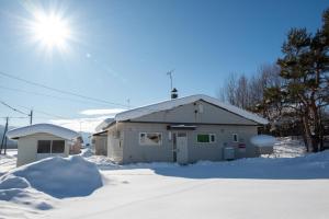 a building in the snow with the sun behind it at Furano Relax Stay A in Furano +51 photos