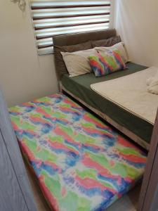 a bedroom with two beds with a colorful blanket at 1 Bedroom Cozy Condo Unit with Netflix & Free Wifi in Trees Residences in Manila