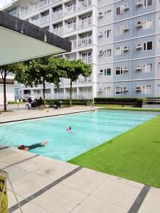 two people swimming in a swimming pool in front of a building at 1 Bedroom Cozy Condo Unit with Netflix & Free Wifi in Trees Residences in Manila