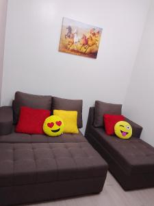 two pillows on a brown couch in a living room at 1 Bedroom Cozy Condo Unit with Netflix & Free Wifi in Trees Residences in Manila