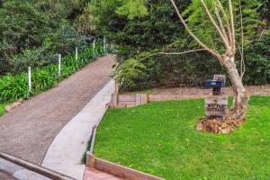 a path leading to a park with a sign in the grass at Wattle Cottage - A Stylish Hinterland Escape in Maleny