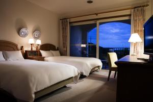 a hotel room with two beds and a large window at Miyako Resort Shima Bayside Terrace in Shima
