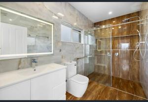 Un baño con inodoro, lavabo y ducha. en Thorneside seaside dream home near the blue sea, en Birkdale