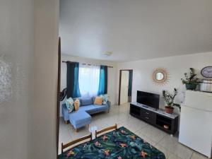 een woonkamer met een blauwe bank en een tv bij Te Anuanua Lodge in Avatoru