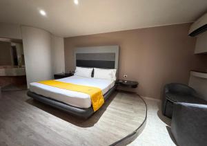 a hotel room with a bed and a chair at Motel Kis in Mexicali