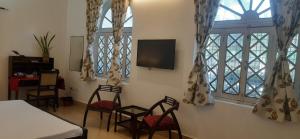 a room with chairs and a tv and windows at Colonial Heritage Bungalow in Prayagraj