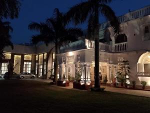 a building with palm trees in front of it at night at Colonial Heritage Bungalow in Prayagraj