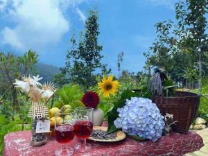 une table avec deux verres de vin et des fleurs dans l'établissement Homestay Khám Phá Y Tý - Only accept Vietnamese customers, à Lao Chải