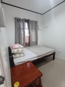 a small room with a bed and a wooden table at The Bocol's House Stay in Sampong