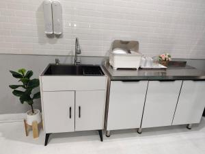 a kitchen with white cabinets and a sink at AuraHome282 in Khlong Luang