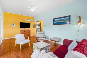 a living room with a couch and a tv at Pacific Waves - Pet Friendly Original Beach House in Kingscliff
