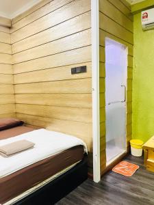 a small room with a bed and a small refrigerator at Suza Hostel in Tumpat