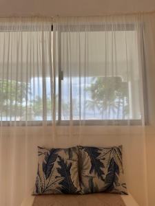 a window with white curtains and a pillow in front of it at Beachfront House in Dahican in Mati