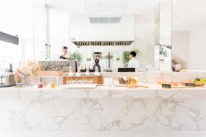 a white counter in a restaurant with people in the background at K Maison Boutique Hotel in Bangkok