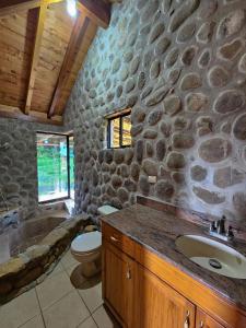 un bagno con pareti in pietra, lavandino e servizi igienici di Grand Saint Bernard Juayúa a Juayúa