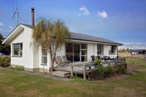 a small white house with a porch and a bench at House Horse & Hound on Argelins in Hanmer Springs