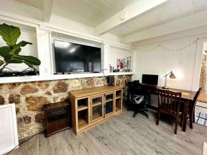 un bureau à domicile avec un bureau et une télévision sur un mur en pierre dans l'établissement Charming Backyard Guest House with Koi Pond, à San Leandro