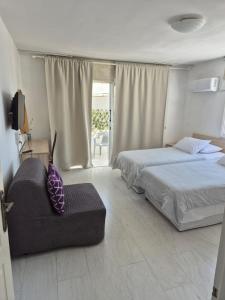 a bedroom with two beds and a couch and a window at Myriama Apartments in Ayia Napa