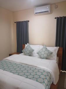 een slaapkamer met 2 witte bedden en blauwe gordijnen bij Bali Oma Living in Denpasar