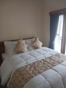 een groot wit bed met kussens en een raam bij Bali Oma Living in Denpasar