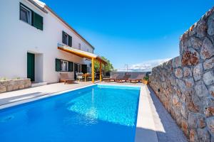 a villa with a swimming pool and a stone wall at Holiday Home 4200-1 for 8 Pers in Lukoran in Lukoran