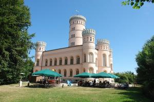 a large building with tables and umbrellas in front of it at Pension Edelstein in Ostseebad Sellin