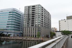 a tall building next to a river with a bridge at Rembrandt Style Yokohama Sakuragicho in Yokohama