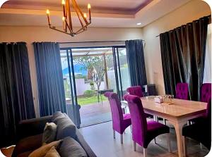 a dining room with a table and purple chairs at Vila Princess, Vimala hills 3bedroom Private Pool, Mountain View, Piano, 0813 delapan 0 satuenam 4 satu 51 in Bogor