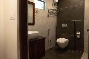 a bathroom with a sink and a toilet and a mirror at Dhyan Village Retreat in Vaikom