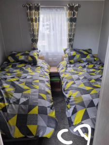 two beds in a small room with a window at Lyons robin hood HV in Meliden