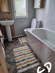 a bathroom with a tub and a toilet and a sink at Lyons robin hood HV in Meliden +8 photos