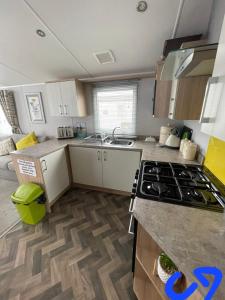 a kitchen with white cabinets and a stove top oven at Lyons robin hood HV in Meliden
